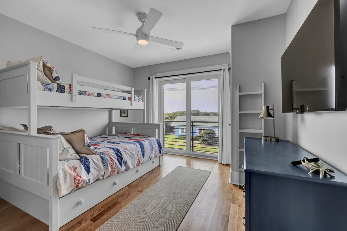 A cheerful bunk room with a large window, a sturdy bunk bed, and a dresser. The space feels playful and bright, perfect for children to enjoy bedtime stories and cozy nights, while also offering ample storage and comfort.