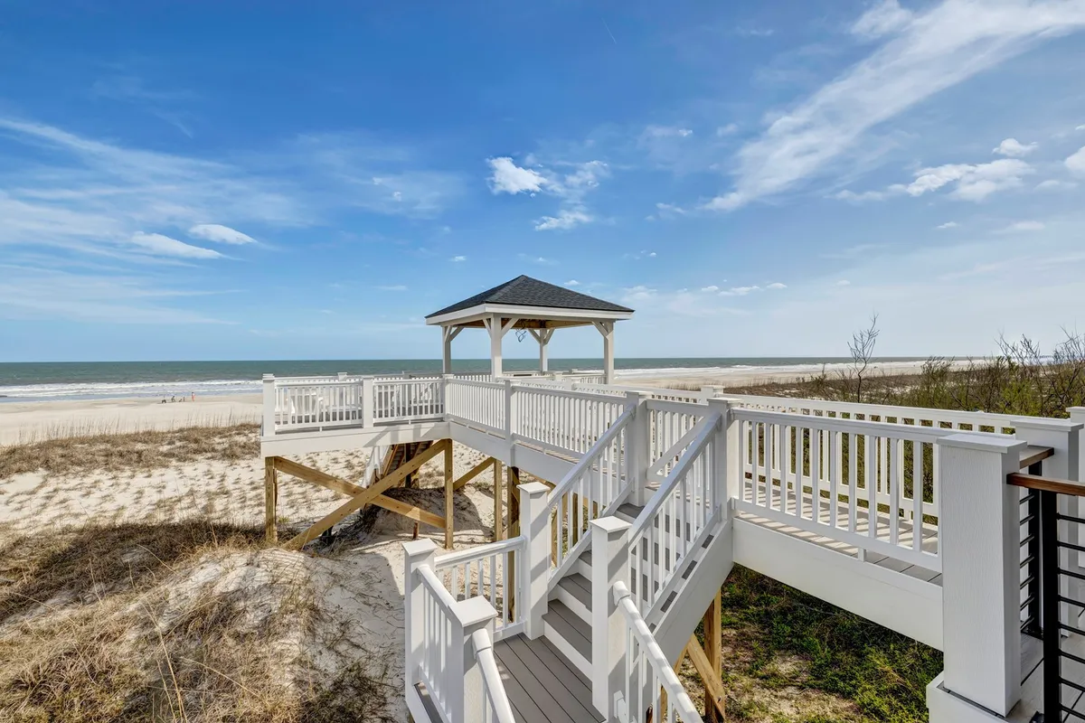 A scenic gazebo perched above a staircase overlooking the ocean, offering a serene spot for guests to gather or relax and soak in sunset views.