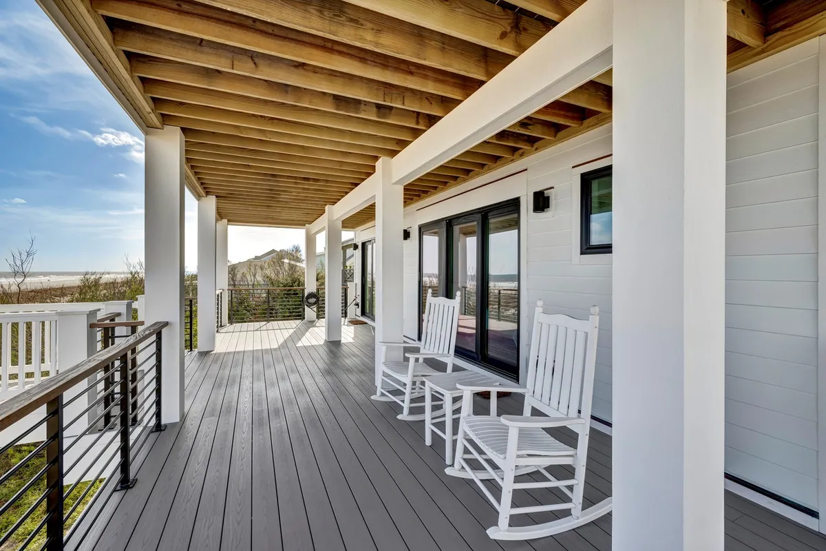 A peaceful exterior deck featuring classic rocking chairs set against a backdrop of natural landscape, with open space and deck railings framing the view. The image radiates serenity and showcases the ideal spot for morning coffee, sunset watching, or simply relaxing with a book. The deck's open, inviting design hints at multiple vantage points from which to enjoy the scenery.