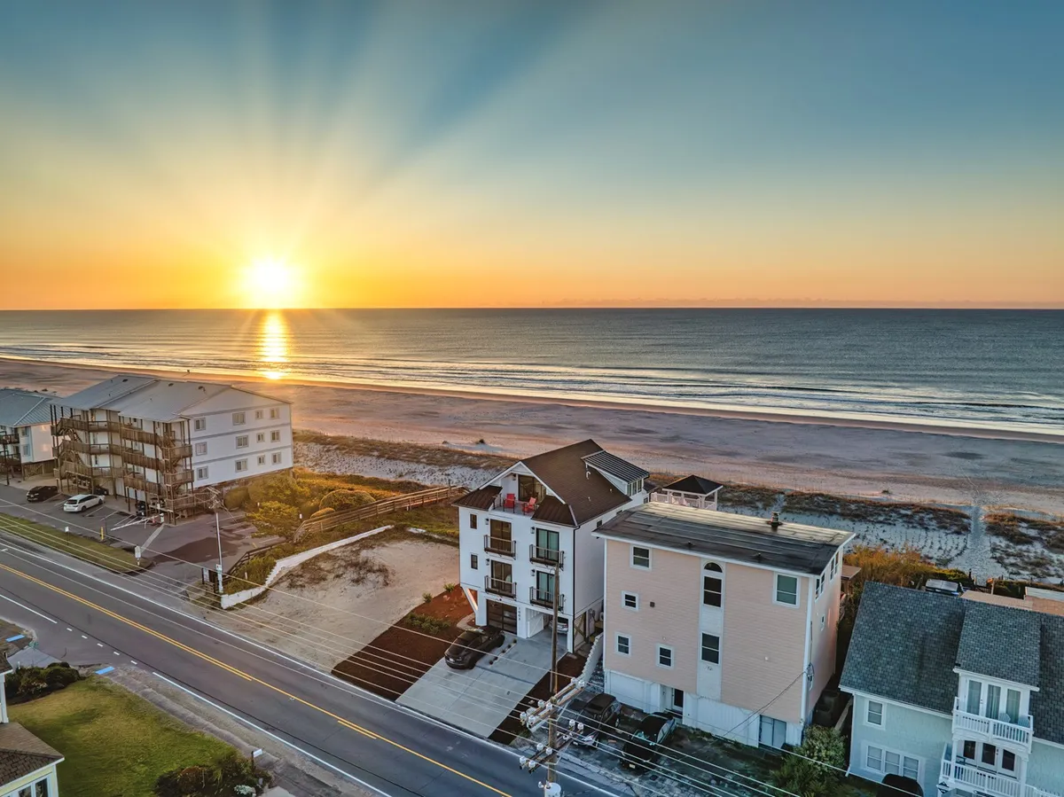 A stunning exterior shot capturing a sunset over calm ocean waves, with beachfront properties lining the shore. This peaceful scene sets the stage for sunset strolls, reflection, and photography moments with friends or family.