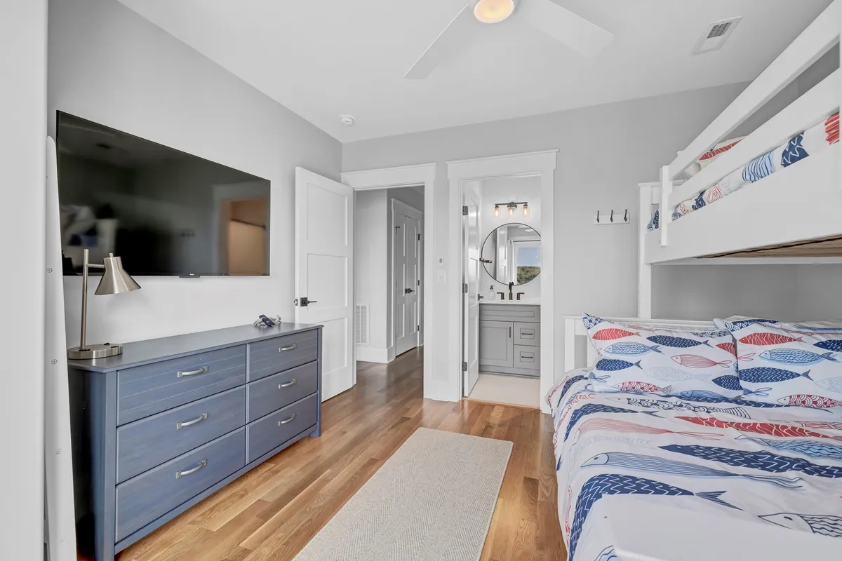 A cozy, kid-ready interior featuring a bunk bed, dresser, and a wall-mounted TV, all arranged in a playful, relaxed configuration. This space promises a comfortable retreat for children to rest or enjoy quiet activities after a day out.