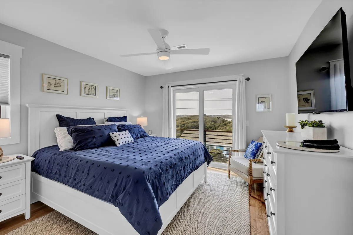 A spacious master bedroom featuring a king-sized bed, large windows that fill the room with natural light, a dressing table, and an inviting armchair. The serene décor and uncluttered layout create an atmosphere of luxury and relaxation, ideal for unwinding after a long day.